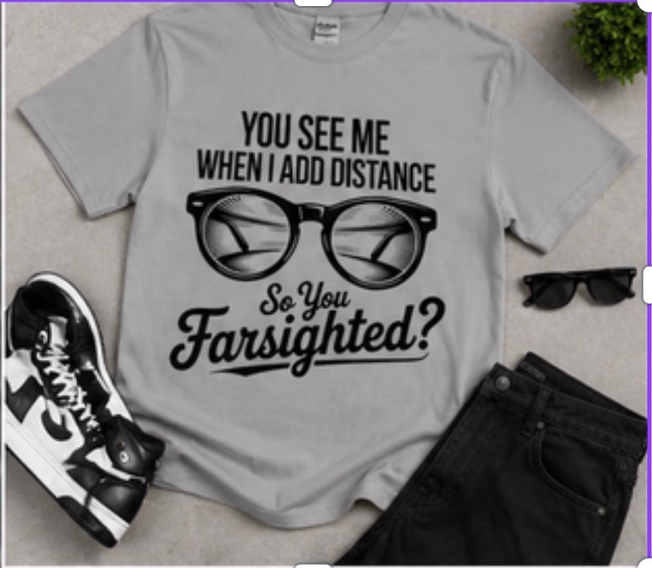 Gray t-shirt with sunglasses graphic and text, paired with black sunglasses and sneakers on a light gray background.