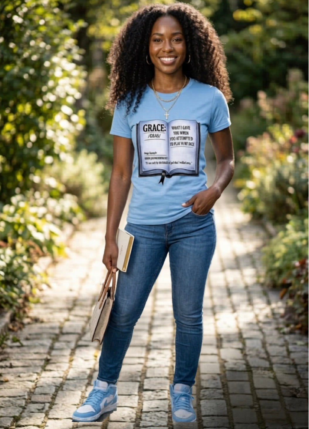 Woman wearing a blue t-shirt with a graphic design, standing outdoors on a sunny day.