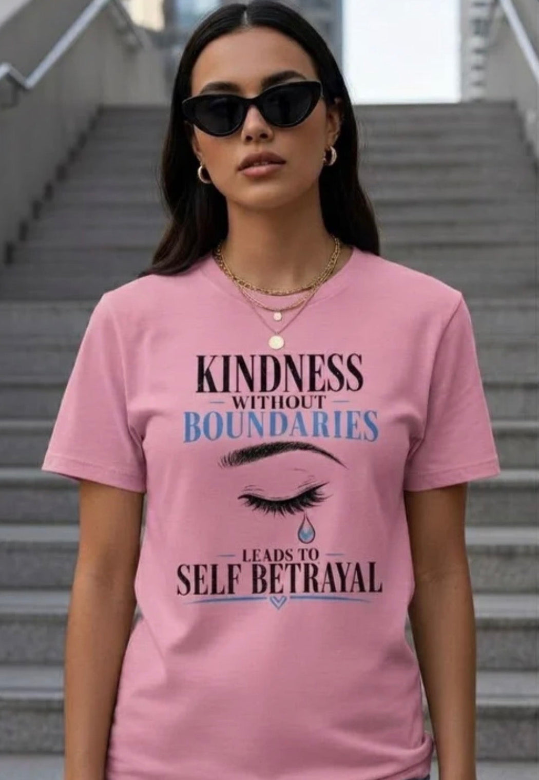 Woman wearing a pink t-shirt with a quote on it, standing on stairs.