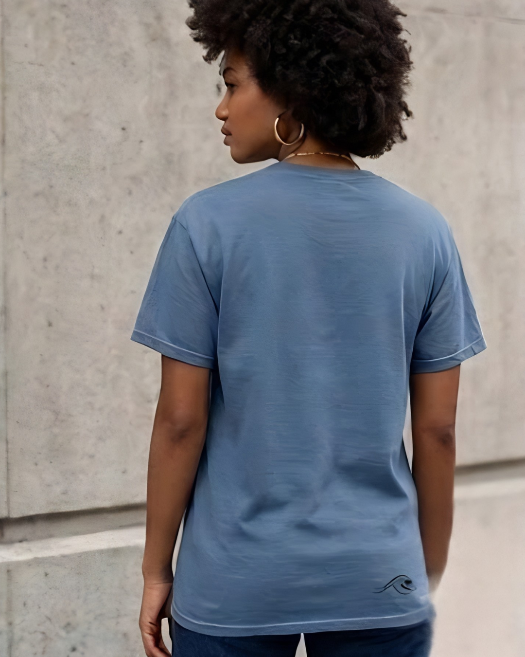 Person wearing a blue t-shirt against a concrete wall